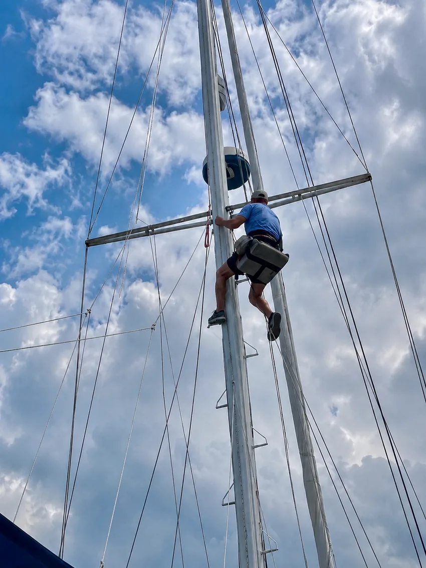 Marine surveyor aloft inspecting sailboat mast and rigging